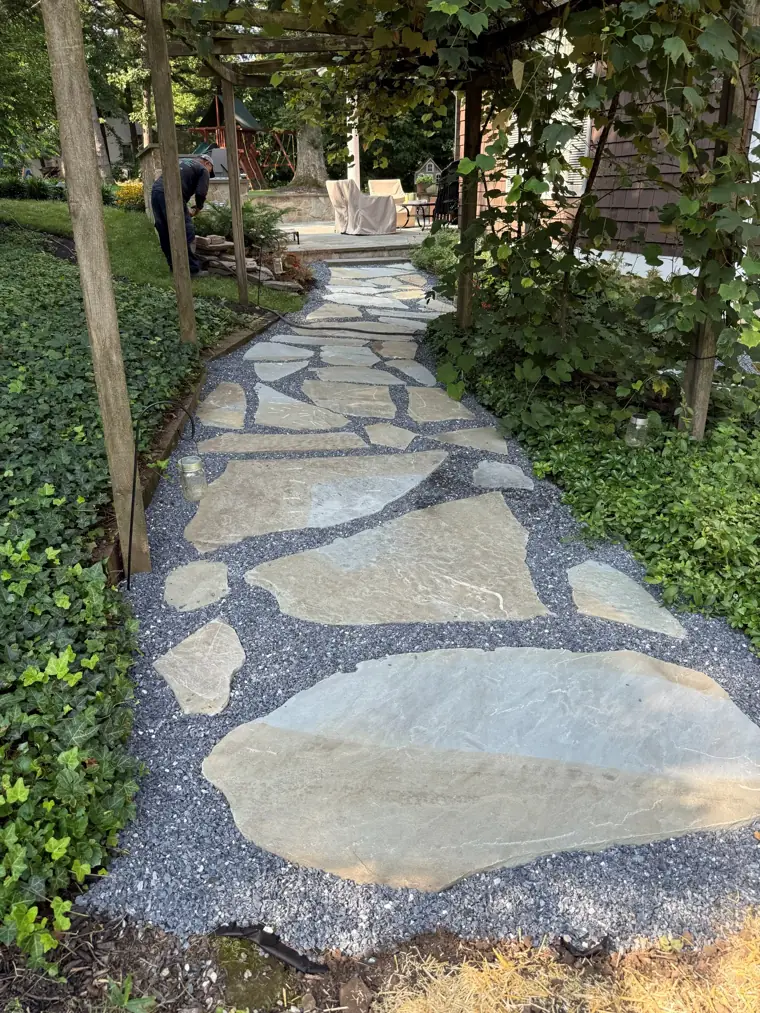 Flagstone path set in river rock, curving through ivy beds under a wooden arbor, built by Jamatte Landscaping in Baltimore County, Maryland